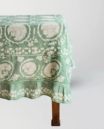 Green floral patterned tablecloth on a wooden table against a white background