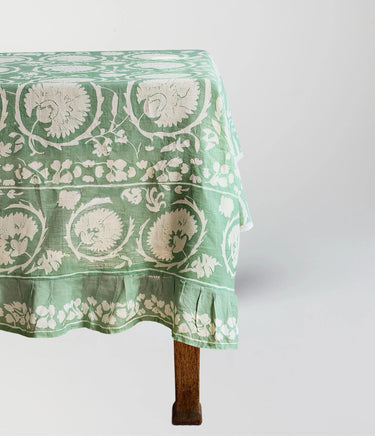Green floral patterned tablecloth on a wooden table against a white background