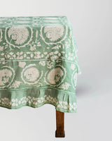Green floral patterned tablecloth on a wooden table against a white background