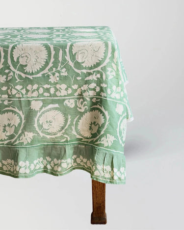 Green floral patterned tablecloth on a wooden table against a white background