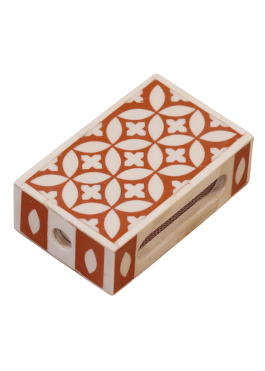 A handmade matchbox holder with a geometric pattern in orange and white colors, equipped with a slot to hold matches.