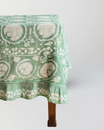 Green floral patterned tablecloth on a wooden table against a white background