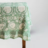 Green floral patterned tablecloth on a wooden table against a white background