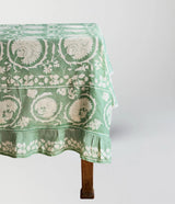 Green floral patterned tablecloth on a wooden table against a white background
